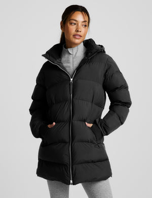 Person wearing a black puffer coat on a light gray background. 