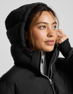 Person wearing a black puffer coat on a light gray background. 