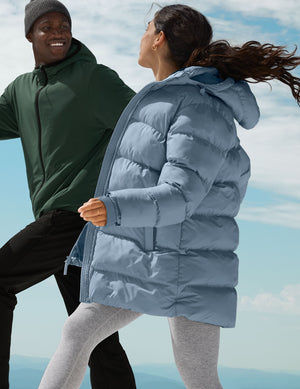 Two people wearing puffer jackets against a blue sky.