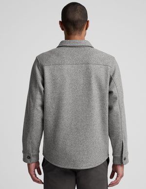 model wearing a gray men's button up jacket over a black shirt on a light gray background. 