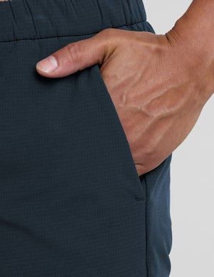 Person wearing navy pants on a plain background. 
