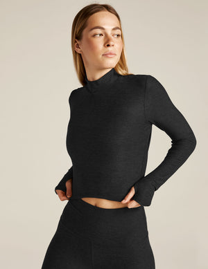 Woman wearing a black long-sleeve top and leggings on a beige background