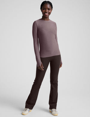model wearing a mauve long-sleeve fitted crew neck top against a plain background.