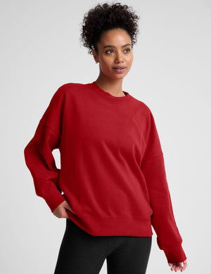 model wearing a red oversized crewneck fleece sweatshirt on a plain background. 