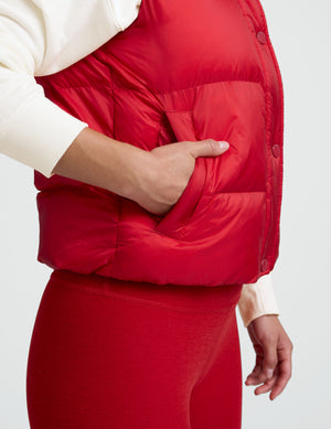 woman wearing a red puffer vest and leggings against a plain background. 