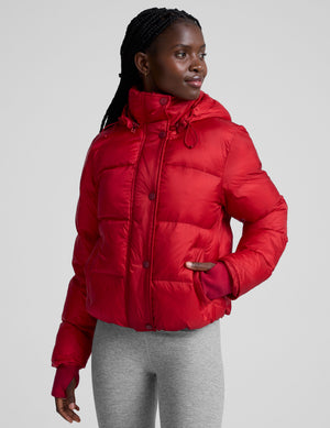 woman wearing a red puffer jacket on a plain background. 