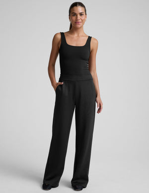 model is wearing a black sleeveless top and black spacer style pants with pockets against a plain background. 