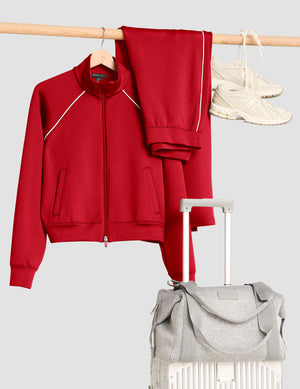 Red tracksuit, gray bag, and white sneakers on a light gray background. 