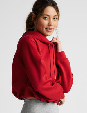 Woman wearing a red hoodie and gray leggings on a white background. 