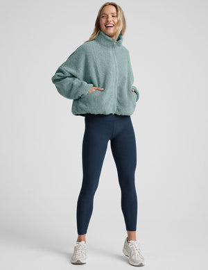 model wearing a blue zip-up fleece jacket against a plain background. 