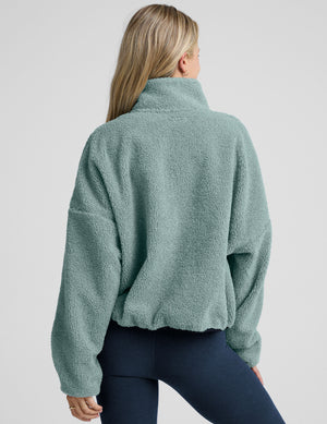 model wearing a blue zip-up fleece jacket against a plain background. 