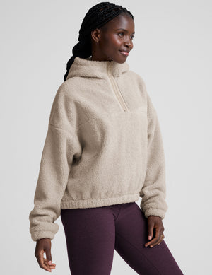 model wearing a beige fleece quarter zip pullover with a plain background. 