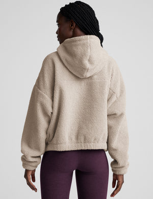 model wearing a beige fleece quarter zip pullover with a plain background. 