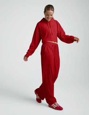 woman wearing a red ribbed cropped hoodie and pants against a plain background. 