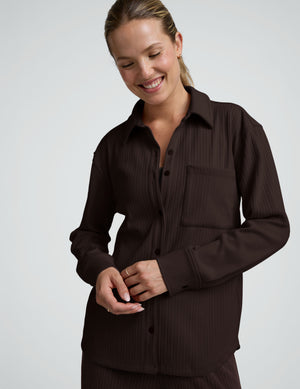 model wearing a brown ribbed button down top and brown ribbed pants against a plain background. 