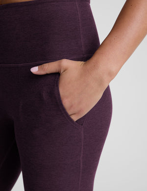 model wearing purple high-waisted bootcut pants with pockets on a plain background. 