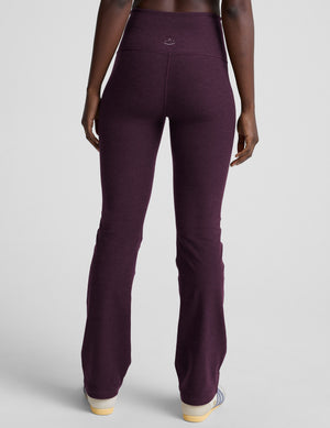 model wearing purple high-waisted bootcut pants with pockets on a plain background. 