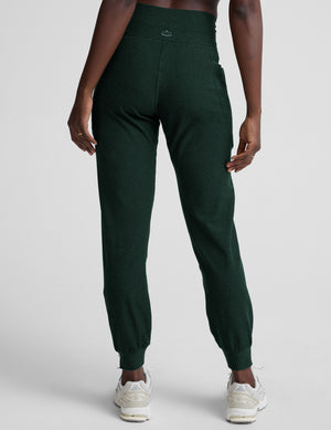 model wearing green midi length joggers with a drawcord at the waistband against a plain background. 