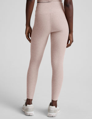 model wearing pink high-waisted leggings with a front crossover detail on a plain background. 