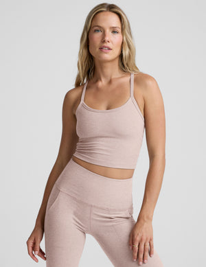 pink slim racerback cropped tank top and pink high-waisted midi leggings on a plain background. 