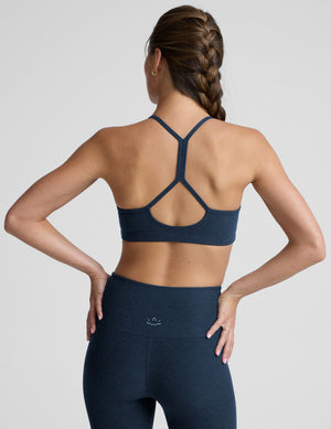 person wearing a blue slim racerback bra with leggings against a plain background. 