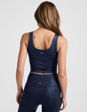 Woman wearing a navy blue viper printed cropped tank and legging on a plain background. 